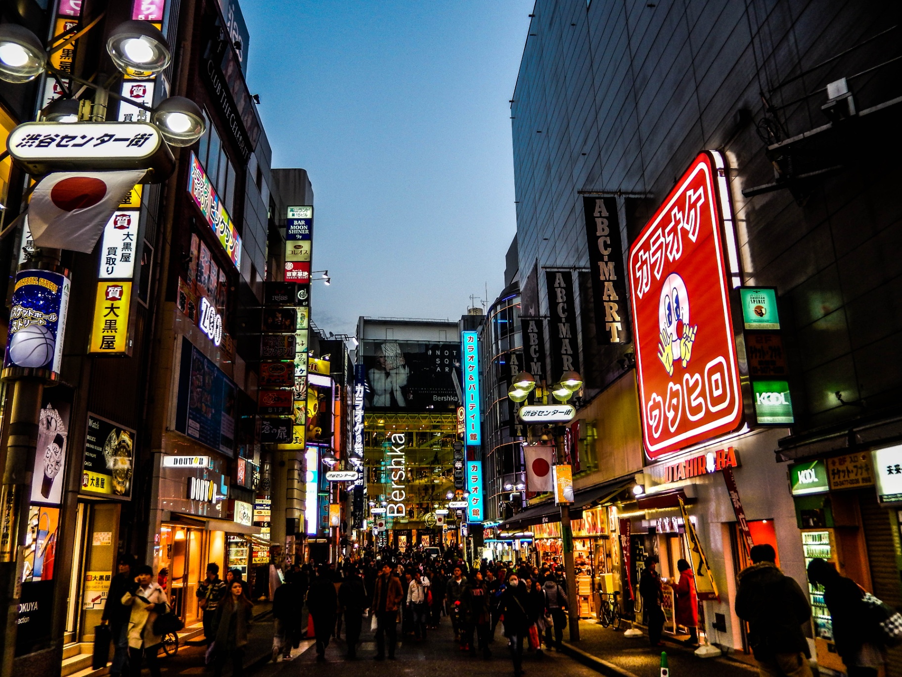 Illuminated signs along a busy street in Shibuya
