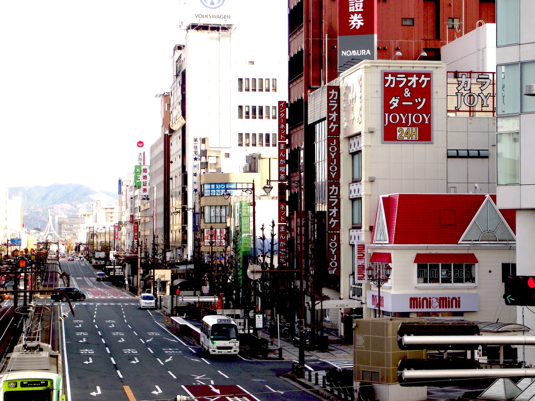 A Japanese city street with buses, shops, and signs